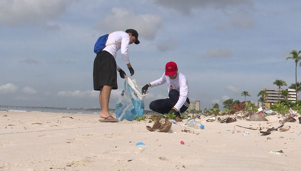 Alunos do proeto "Oceano de Plástico" recolhendo resíduos na praia - Foto: Reprodução/TV Pajuçara